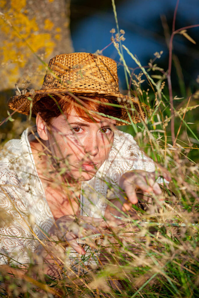 WELLNESS, RELAXATION, WOMAN WITH A STRAW HAT IN THE GRASS IN THE COUNTRYSID - Photo, Image