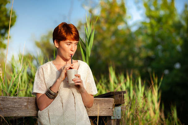 WOMAN DRINKING STRAW IN THE COUNTRYSIDE - Photo, Image