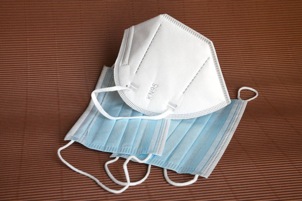 wit KN95 of N95 masker met antiviraal medisch masker voor bescherming tegen coronavirus op bruine achtergrond. Chirurgisch beschermend masker. preventie van de verspreiding van virus en pandemie COVID-19. - Foto, afbeelding