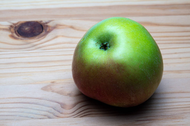 an Apple shoan Apple shot from the side on a wooden backgroundt from the side on a wooden background - Foto, Imagen