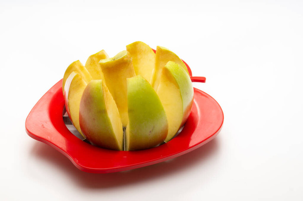 an Aan Apple partially cut with an Apple cutter on a white backgroundpple partially cut with an Apple cutter on a white background - Photo, image