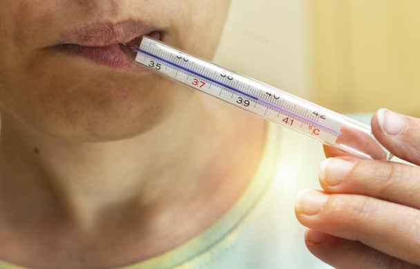 женщина измеряет температуру и в термометре показывает высокую температуру 39 С, так что она была заражена коронавирусом
 - Фото, изображение