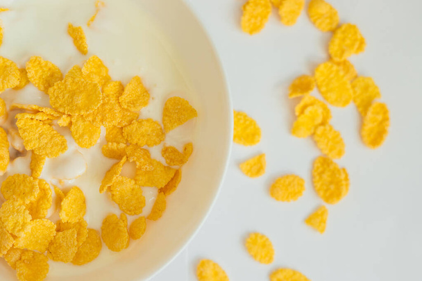 Cornflakes with milk in a deep white bowl. White background. Delicious and healthy Breakfast. - Fotografie, Obrázek