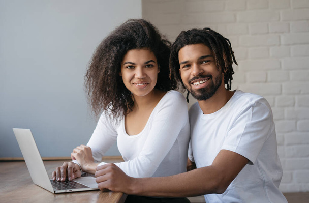 Portret szczęśliwych Afroamerykanów korzystających z laptopa, patrzących w kamerę i uśmiechających się, uczących się z domu. Koncepcja edukacji internetowej  - Zdjęcie, obraz