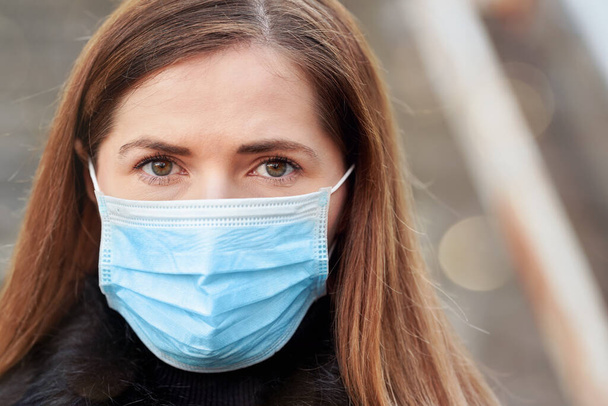 Young woman wearing disposable blue virus face mouth nose mask, closeup portrait. Coronavirus covid-19 outbreak prevention concept - Foto, Imagen