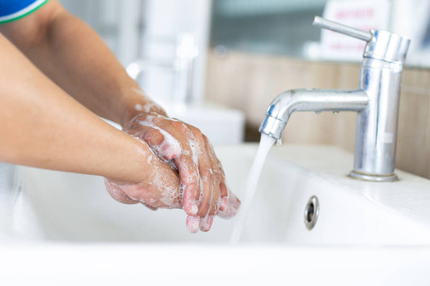 Der Mensch wäscht sich die Hände in einer Spüle, um das Colona-Virus für sanitäre Zwecke zu desinfizieren und die Ausbreitung von COVID-19 in der ganzen Welt zu verringern, Hygiene, Sanitärkonzept. - Foto, Bild