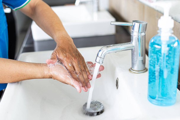 De mens wast zijn handen in een gootsteen, reinigt het colona virus voor sanitaire voorzieningen en vermindert de verspreiding van COVID-19 verspreid over de hele wereld, Hygiëne, Sanitatie concept. - Foto, afbeelding