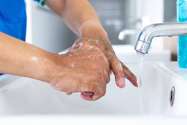 Człowiek myje ręce w zlewie oczyszczając wirusa colony do celów sanitarnych i zmniejszając rozprzestrzenianie się COVID-19 na całym świecie, Higiena, Koncepcja sanitarna. - Zdjęcie, obraz