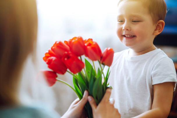 Mały syn gratuluje matce i daje bukiet kwiatów tulipany. Szczęśliwego Dnia Matki. Rodzinne wakacje i wspólne spędzanie czasu. - Zdjęcie, obraz