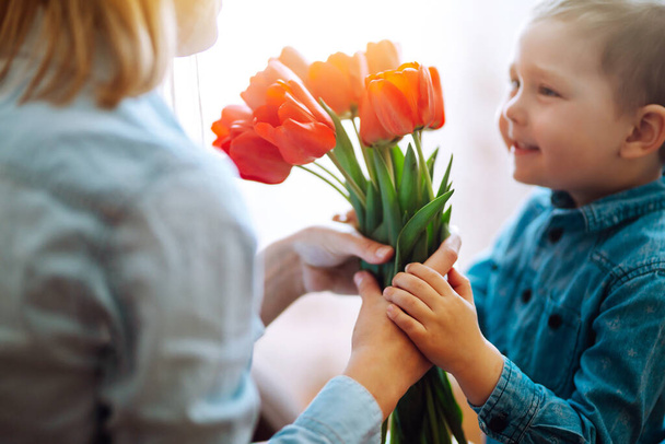 Tulpenstrauß für Mama. Der kleine Sohn gratuliert der Mutter und überreicht einen Strauß Tulpen. Glücklicher Muttertag. Familienurlaub und Zweisamkeit. - Foto, Bild