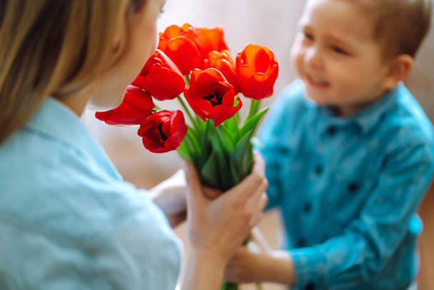 Bouquet of tulips for mom. Little son congratulates mother and gives a bouquet of flowers tulips. Happy mother's day. Family holiday and togetherness. - Φωτογραφία, εικόνα