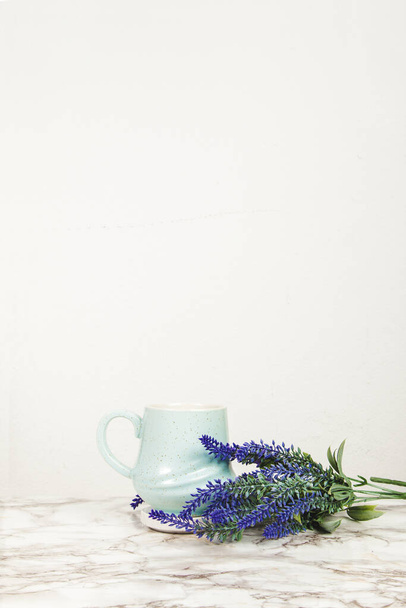 Lavendelblüten und pastellblauer Becher auf einem Marmortisch - Foto, Bild