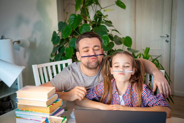 funny daddy helps daughter with distance learning  - 写真・画像