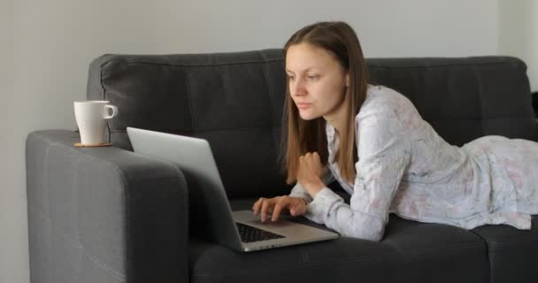 Serious young woman freelancer working on freelance from home typing email on laptop, focused girl using computer for study online at home on couch, female user busy on distance internet job. - Кадри, відео