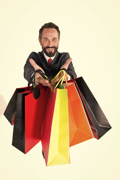 Paper colored bags in hand of sales manager isolated. Seasonal sales for shopping. Guy in suit with your purchases. Internet sales delivery to wardrobe with personal consultant - Photo, Image