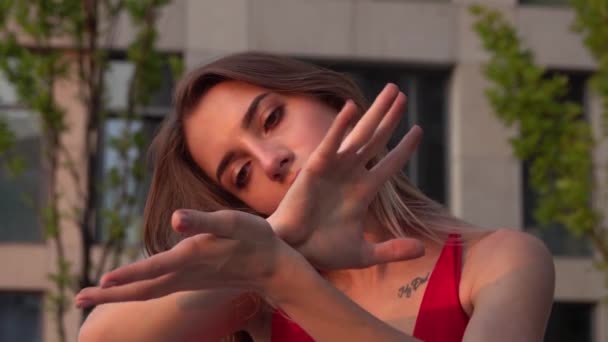 Beautiful young girl dancing on the street of a modern building of a business center in the sunset light. Close up. Slow motion. - Filmagem, Vídeo