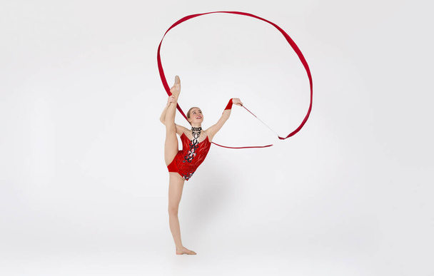 Atraktivní gymnastka s stuhou připravuje pro profesionální soutěž, bílé pozadí - Fotografie, Obrázek