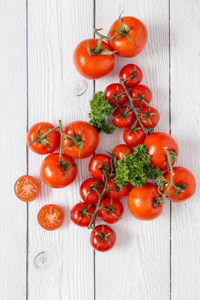 Composition of red tomatoes with green parsley on white wooden surface as background. Blank for menu at restaurant. Concept of fresh ingredients picture - Zdjęcie, obraz