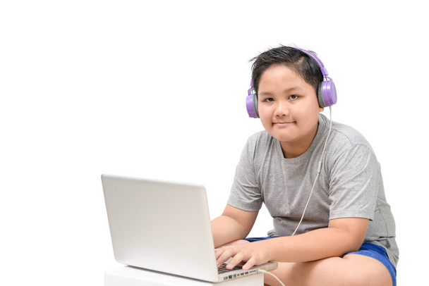 Elhízott fiú diák viselni fejhallgató tanulmány online tanár elszigetelt fehér háttér, Boldog fiú diák játszik számítógép headset és élvezze az online nyírás elérési utat. Kovid-19 - Fotó, kép