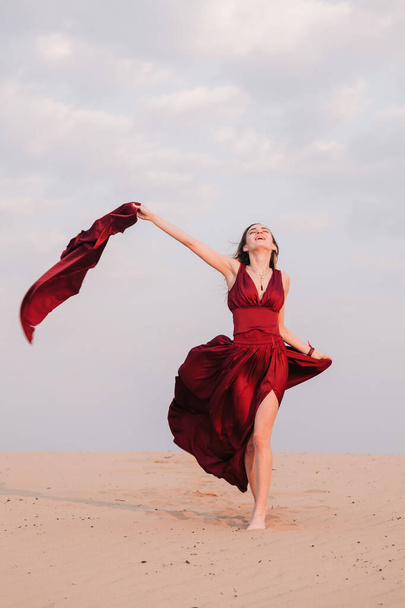 girl in the desert at sunset in a red dress developing in the wind - Foto, imagen