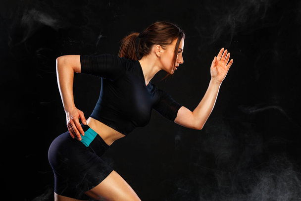 Sprinter and runner girl. Running concept. Woman running on the black background. The concept of a healthy lifestyle and sport. Woman in sportswear. - Фото, зображення