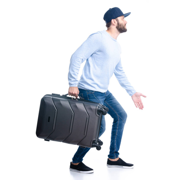 Man in jeans holding travel suitcase goes walking - Фото, зображення