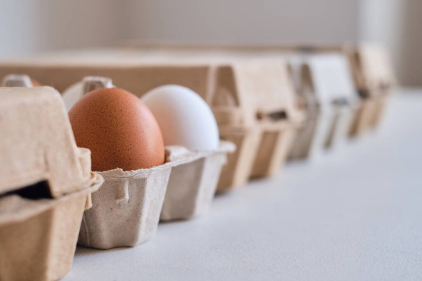 Cardboard boxes with chicken eggs. Boxes with uncooked eggs in table. Natural organic farm product. Preparing for Easter holiday. Fresh food delivery, carton package. Raw ingredient for cooking eat - 写真・画像