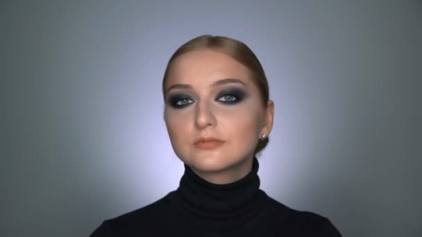 Hermosa mujer con maquillaje ojos ahumados posando en la cámara - Metraje, vídeo