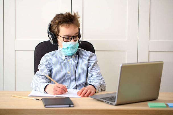 Távolsági tanulás online oktatás. iskolás fiú orvosi maszkban otthon tanul, koronavírus karantén - Fotó, kép