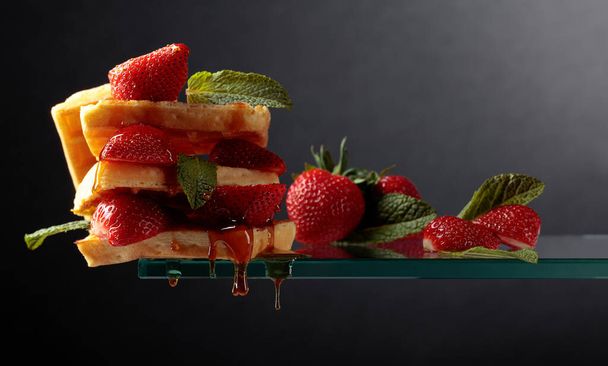 Waffeln mit Erdbeeren und Honig garniert mit frischer Minze.  - Foto, Bild