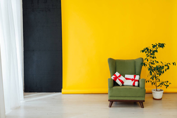 stoel met een geschenk in het interieur van de kamer met een gele achtergrond - Foto, afbeelding