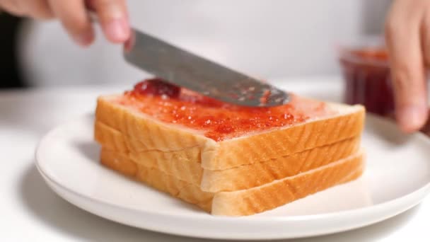 Erdbeermarmelade auf einer Scheibe Brot verteilen. - Filmmaterial, Video