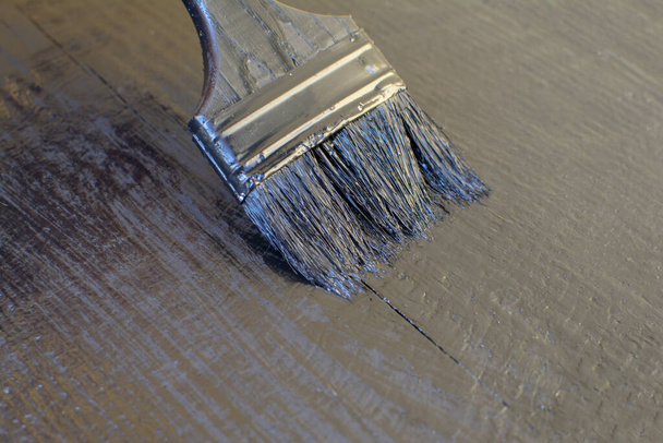 Zwarte verf en penseel op een houten ondergrond - Foto, afbeelding