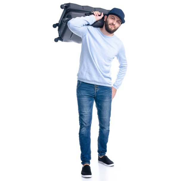 Hombre en jeans sosteniendo la maleta de viaje de pie
 - Foto, imagen