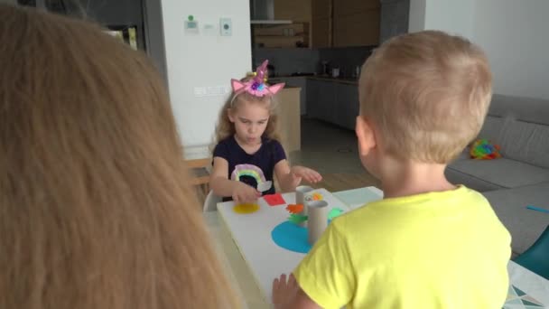 babysitter en kleine kinderen jongen en meisje spelen actieve worstelaar bordspel - Video