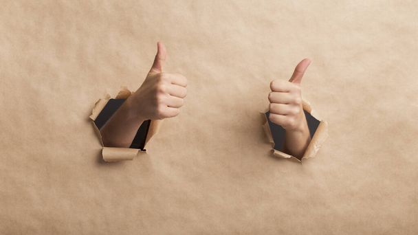 Hands showing thumbs up over cardboard wall, safety delivery - Photo, Image