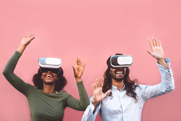 Happy couple using virtual reality headset outdoor - Trendy people having fun with innovated vr googles technology - Tech entertainment and 3d game experience concept - Fotoğraf, Görsel