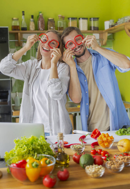 Schöner Mann und Frau, die lachen und Paprika-Gläser tragen - Foto, Bild