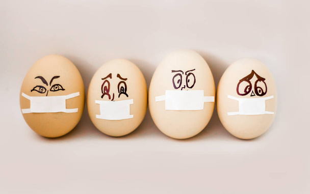 Пасхальні яйця 2020 з концепцією захисту Коронавірусу COVID19. Зробіть собі пасхальні яйця в масці для святкування Великодня. Пасхальні курячі яйця, медичні маски, з лихим виразом обличчя. Поняття Eas - Фото, зображення