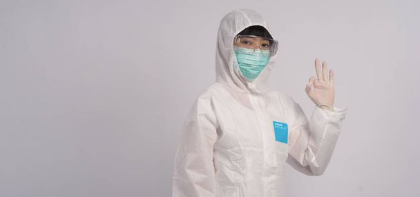 Asian woman doctor in PPE suit with hood and wearing medical mask and gloves for best protection from chemical or virus such as coronavirus or covid-19 and represent virus specialist and white background.  - Photo, Image