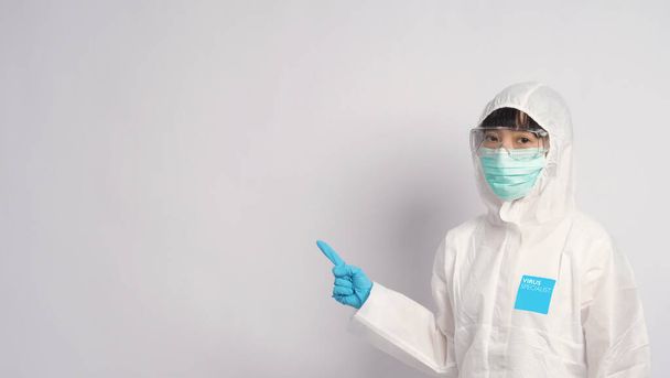 Aasialainen naislääkäri PPE-puvussa, jolla on huppu ja lääketieteellinen naamio ja käsineet parhaan suojan saamiseksi kemialliselta tai virukselta, kuten koronavirukselta tai covid-19:ltä, ja joka edustaa virusspesialistia ja valkoista taustaa
.  - Valokuva, kuva