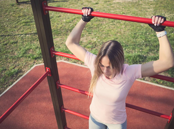 Jeune femme athlétique faisant de l'exercice sur des barres murales dans le parc
 - Photo, image