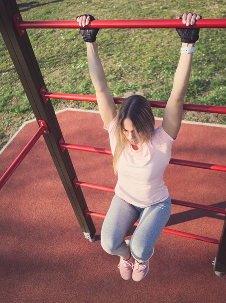 Mujer atlética joven haciendo ejercicio en las barras de pared en el parque
 - Foto, Imagen