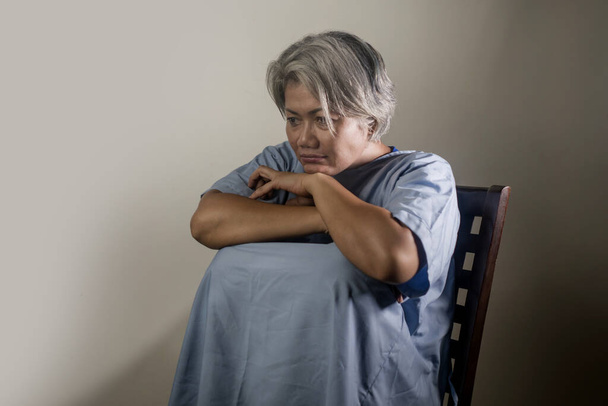 dramatický portrét atraktivní smutné a depresivní dospělé ženy s šedými vlasy v bolestech trpící duševní poruchou nebo depresí problém nošení pacientské šaty pocit nevolnosti a opuštěnosti - Fotografie, Obrázek