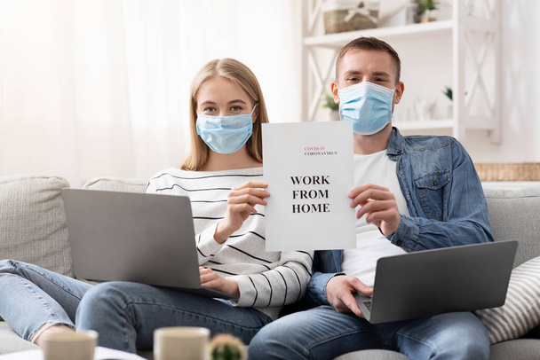 Young employees in protective masks holding placard WORK FROM HOME - Foto, Imagem