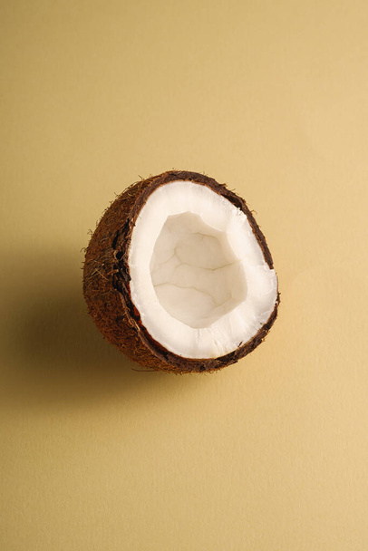 Jednoduché kokosové ovoce na smetanově žlutém prostém pozadí, abstraktní jídlo tropické koncepce, úhel pohledu kopírovat prostor - Fotografie, Obrázek