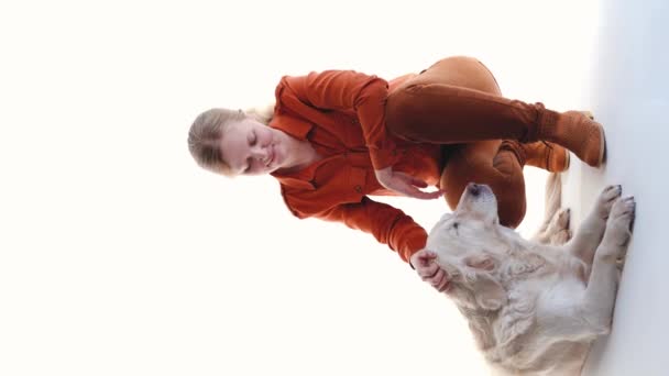 Liebe zu Haustieren. Studioporträt einer Frau und eines Golden Retrievers im Studio auf weißem Hintergrund, vertikales Video - Filmmaterial, Video