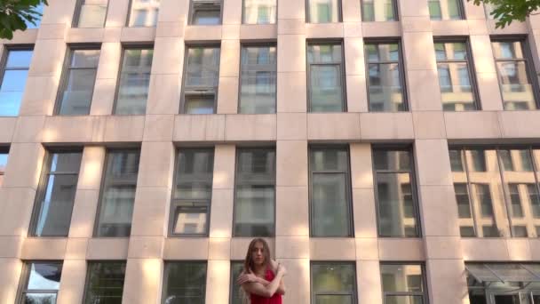 Beautiful young girl dancing on the street of a modern city and is reflected in the water. She is wearing a red dress. Slow motion. - Footage, Video
