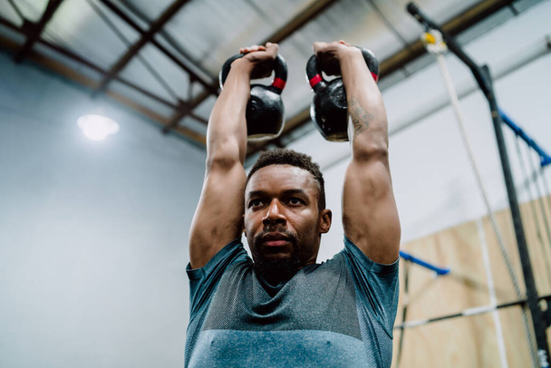 Portrait of young athletic man doing exercise with crossfit kettlebel at the gym. Crossfit, sport and healthy lifestyle concept. - Fotoğraf, Görsel