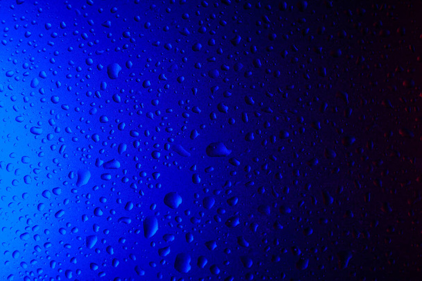 Kapky vody na sklo v modrém neonovém světle. Déšť na sklo na pozadí. Abstraktní fotografie pro backgroun - Fotografie, Obrázek